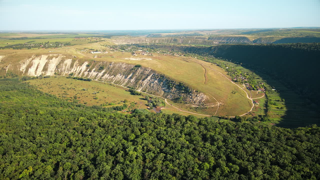 Aerial drone view of nature, valley with river and village, hills and fields, greenery, Moldova