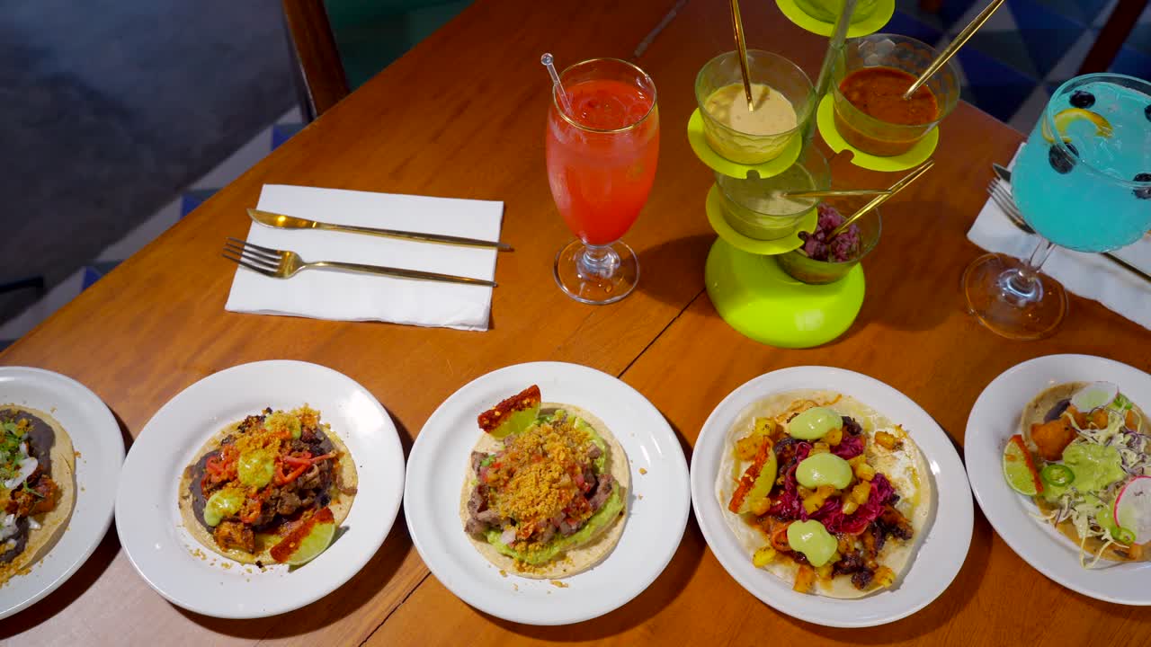 Mexican tacos in restaurant table with cocktails and salsas top slider shot