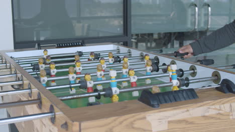 mid shot of employees playing table football inside the game room of a modern corporate office