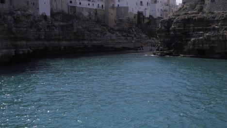 cámara moviéndose hacia arriba desde las olas del mar hacia una vista panorámica de polignano una mare