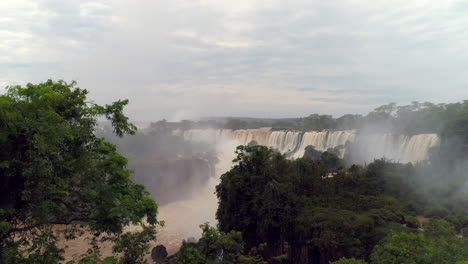 drone emerging from behind trees, unveiling the breathtaking iguazu falls