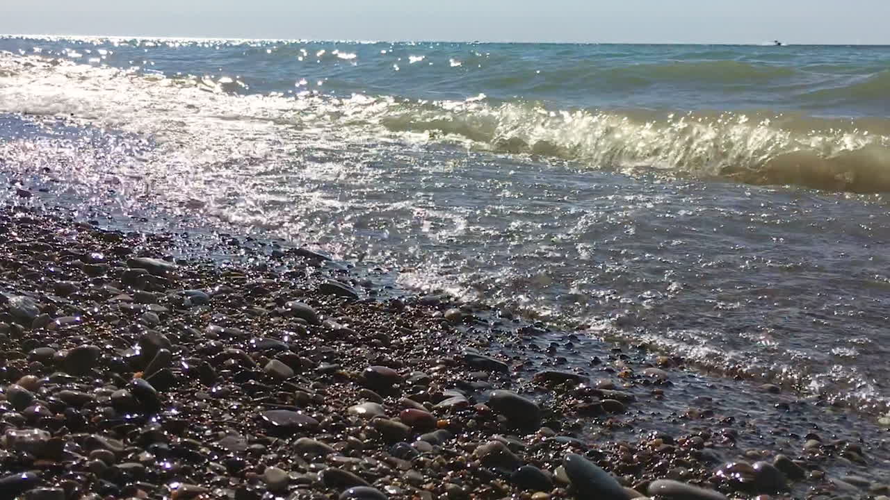 волны разбиваются в озере на песчаном пляже в замедленном движении.