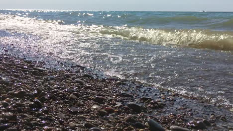 las olas chocan en el lago en la playa de guijarros en cámara lenta