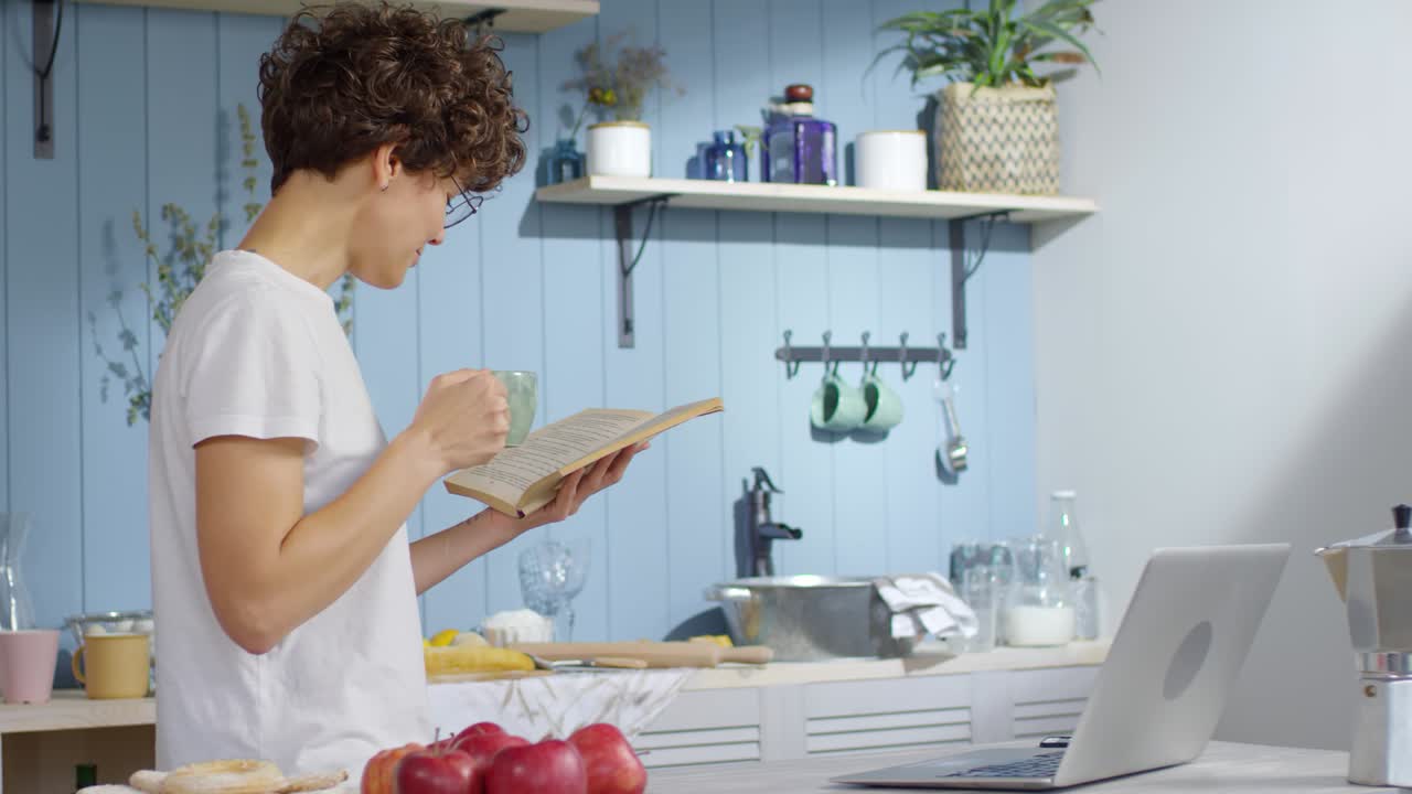 mujer leyendo un libro y bebiendo café en la cocina