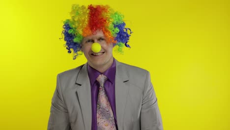 el payaso empresario empresario jefe en peluca ajusta su corbata. fondo amarillo