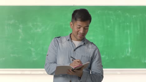 Profesor-Masculino-En-El-Aula-Dando-Una-Lección-O-Conferencia-De-Clase-Universitaria-O-Universitaria-Sosteniendo-Un-Cuaderno-O-Registrándose