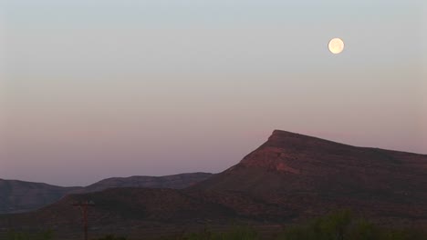 longshot of the moon over a rocky landscape 1