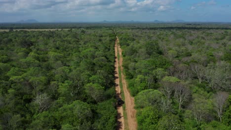 largo camino recto de arena con jeep explorando el exuberante parque nacional yala