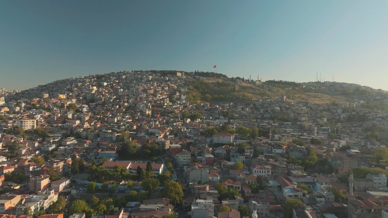 Vista aerea di Smirne in una rotonda con ingorgo stradale e traffico automobilistico congestionato nell'ora di punta, con un'inclinazione verso l'alto che rivela la collina del paesaggio urbano.