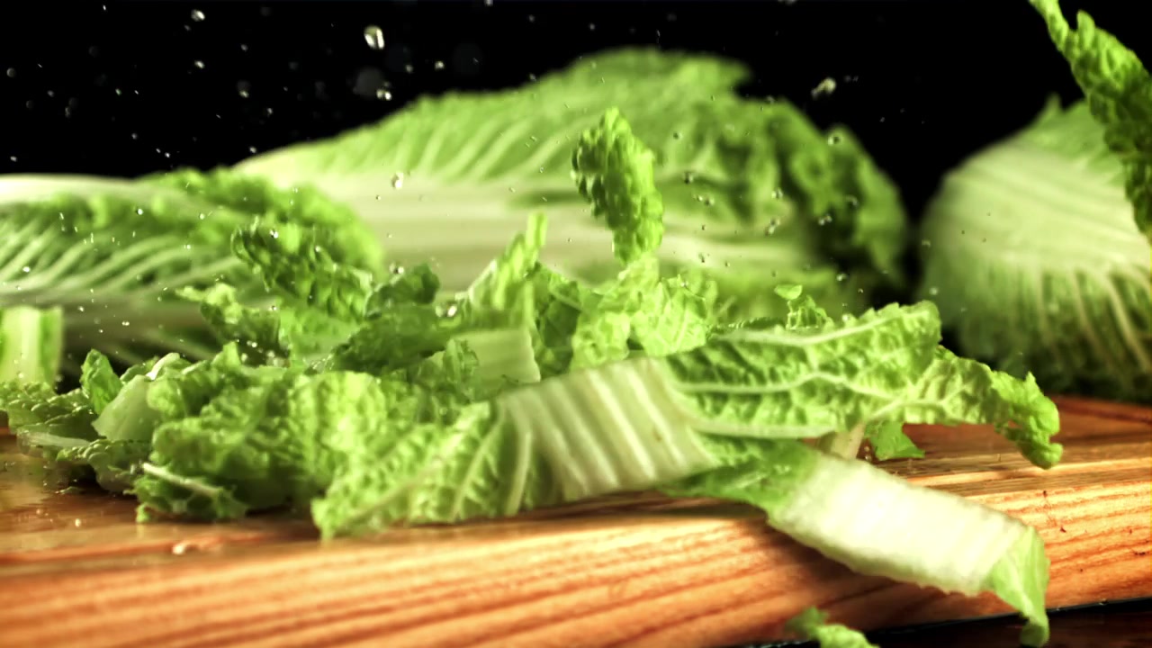 Chopped Chinese Cabbage Falling onto a Wooden Cutting Board in Slow Motion