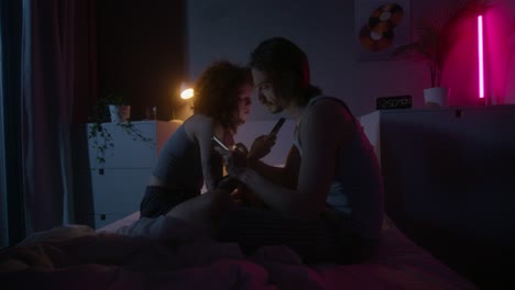 couple using phones in bed at night