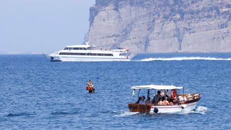 tourist boat cruising near cliffs and yacht