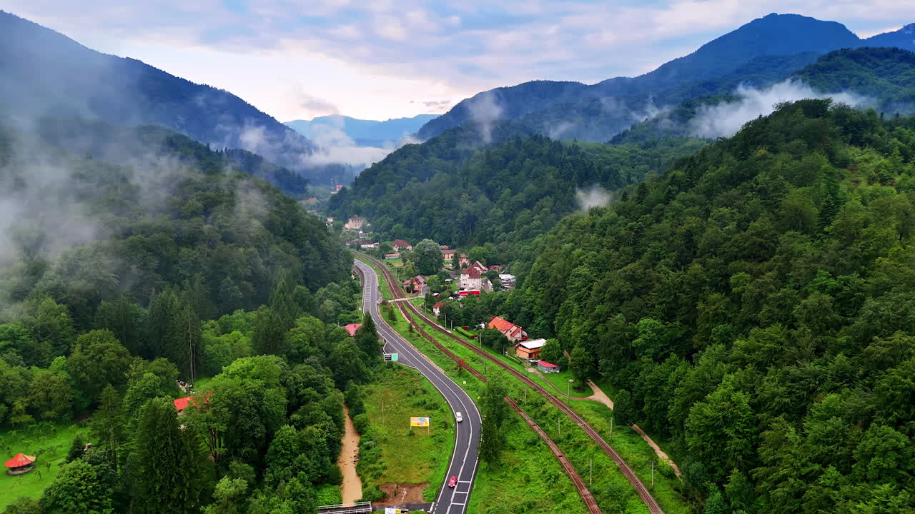 Winding mountain road through greenery. A winding road weaves through lush forests and hills, revealing nature's beauty under a cloudy sky