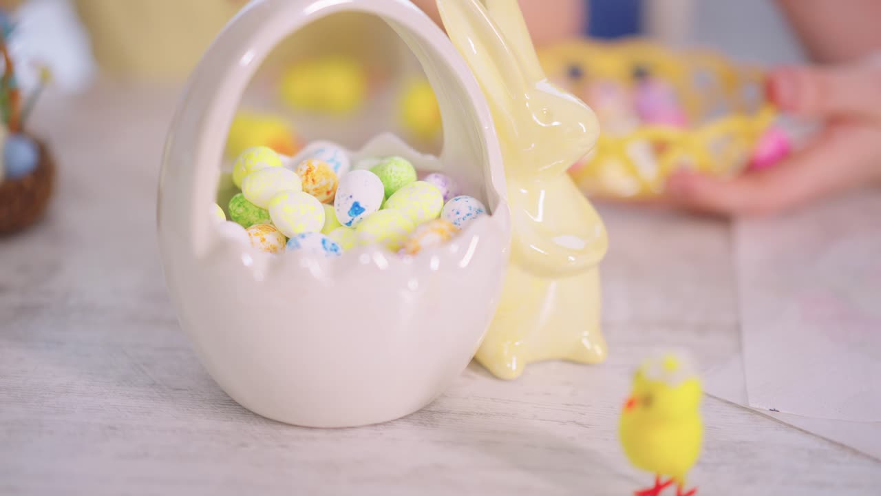 Child's Hand Filling Easter Basket with Colorful Candy Eggs