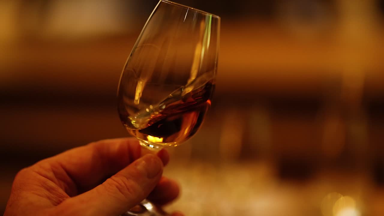 mano sosteniendo una copa de whisky en un entorno elegante