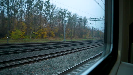 view of empty railways through glass window of a moving train during autumn