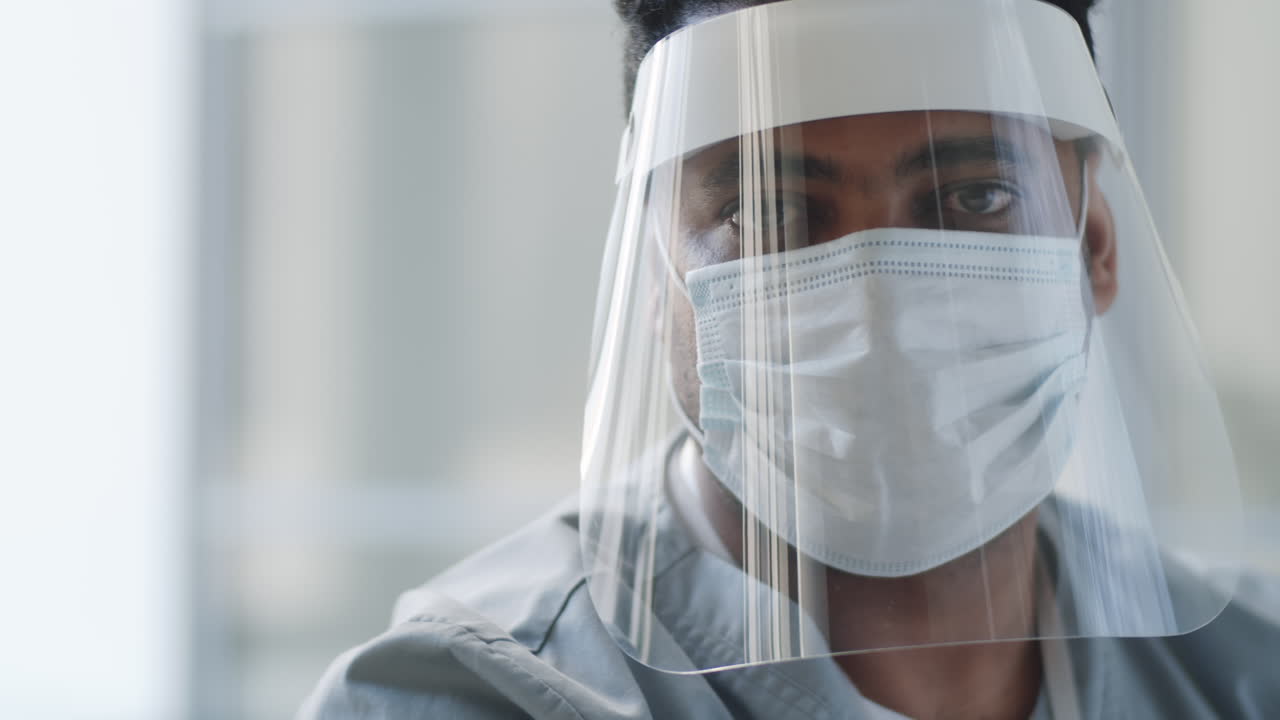 retrato de un médico con escudo facial y máscara en el trabajo