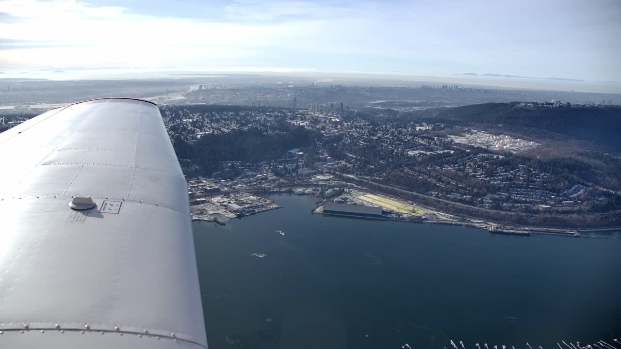 vista del ala de un pequeño avión volando sobre port moody, bc - día soleado