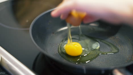 egg is cracked into a pan with oil