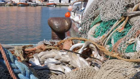 farbige fischernetze, die auf dem pier in der nähe des bootes und des pollers gestapelt sind, um die festmacherleinen zu wickeln