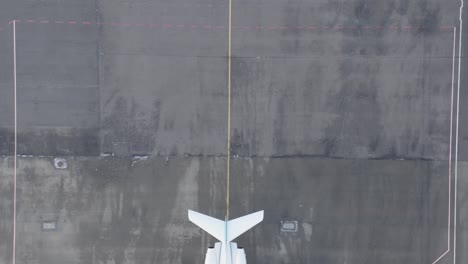 antena de arriba hacia abajo que revela un jet privado blanco estacionado en asfalto gris en la base aérea