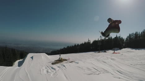 Follow-camera-shot-of-Snowboarder-jumping-and-performing-a-360-spin-at-Grouse-mountain-park-in-slow-motion