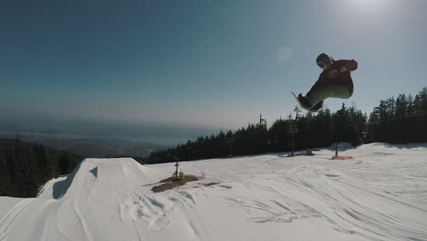 Siga-La-Toma-De-La-Cámara-Del-Snowboarder-Saltando-Y-Realizando-Un-Giro-De-360-Grados-En-El-Parque-De-Montaña-Grouse-En-Cámara-Lenta