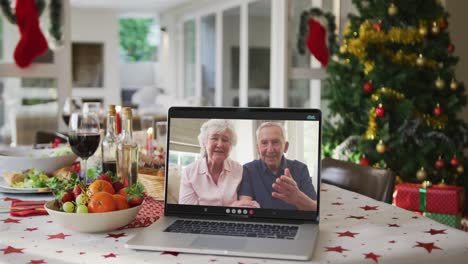 Feliz-Pareja-De-Ancianos-Caucásicos-En-El-Portátil-Tumbado-En-La-Mesa-De-Navidad