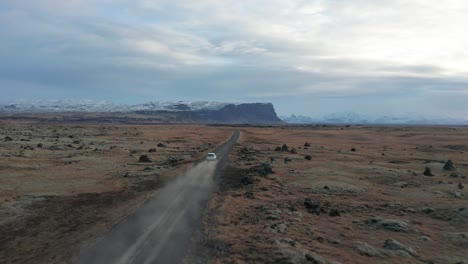 4k drone video of car driving away on a dirt road in iceland