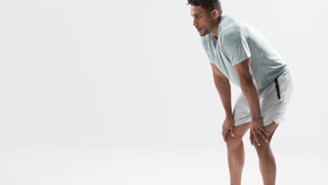 young biracial athlete man takes a break from exercising on a white background, with copy space