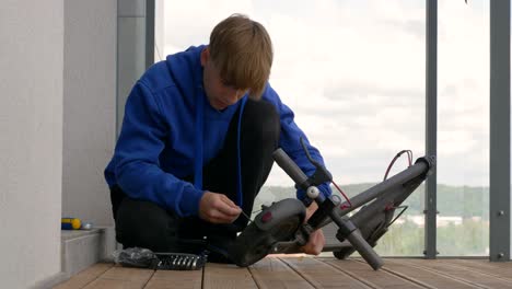 Teenage-boy-tries-to-take-off-electric-scooter-tire