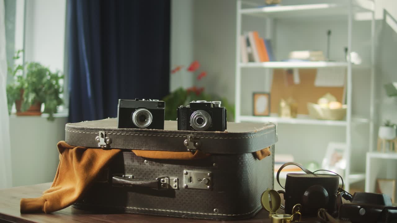 Two Vintage Cameras Resting on an Old Suitcase