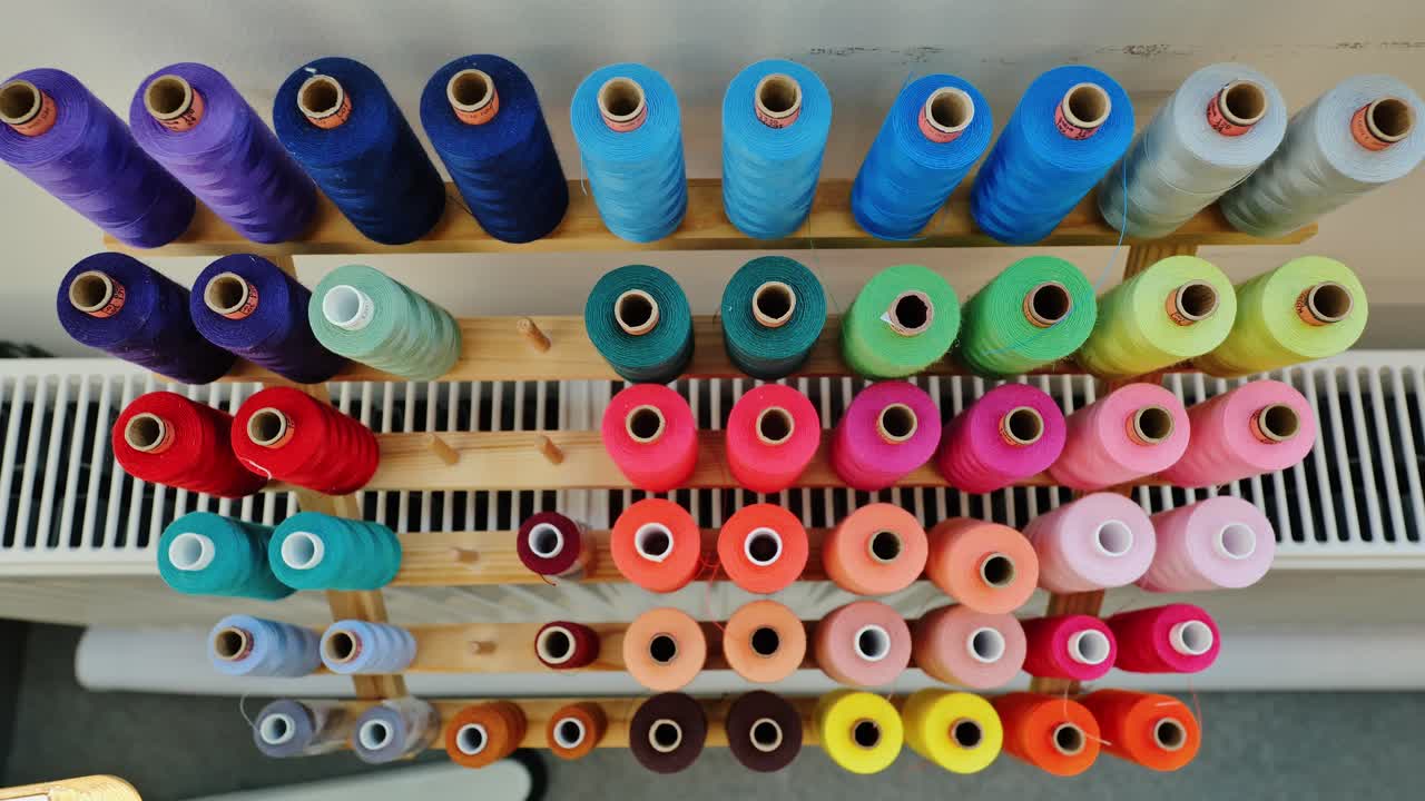 Colorful sewing threads form vibrant pattern, minimalist studio overhead display