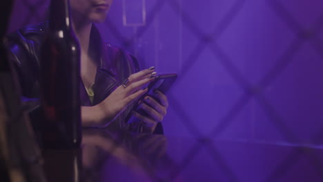 close up of a beautiful girl using mobile phone while sitting at disco club