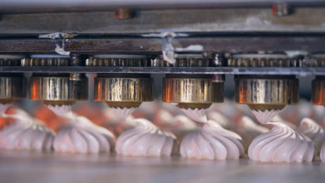 rotating metal nozzles lay creamy substance on the conveyor belt to create beautifully-shaped marshmallows. close up. food factory concept.