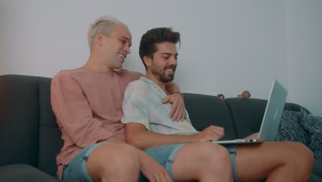 happy gay couple watching laptop