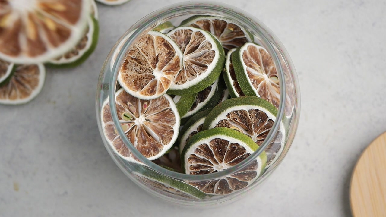 Hand Picking Up Dried Lime Slice from Glass Jar