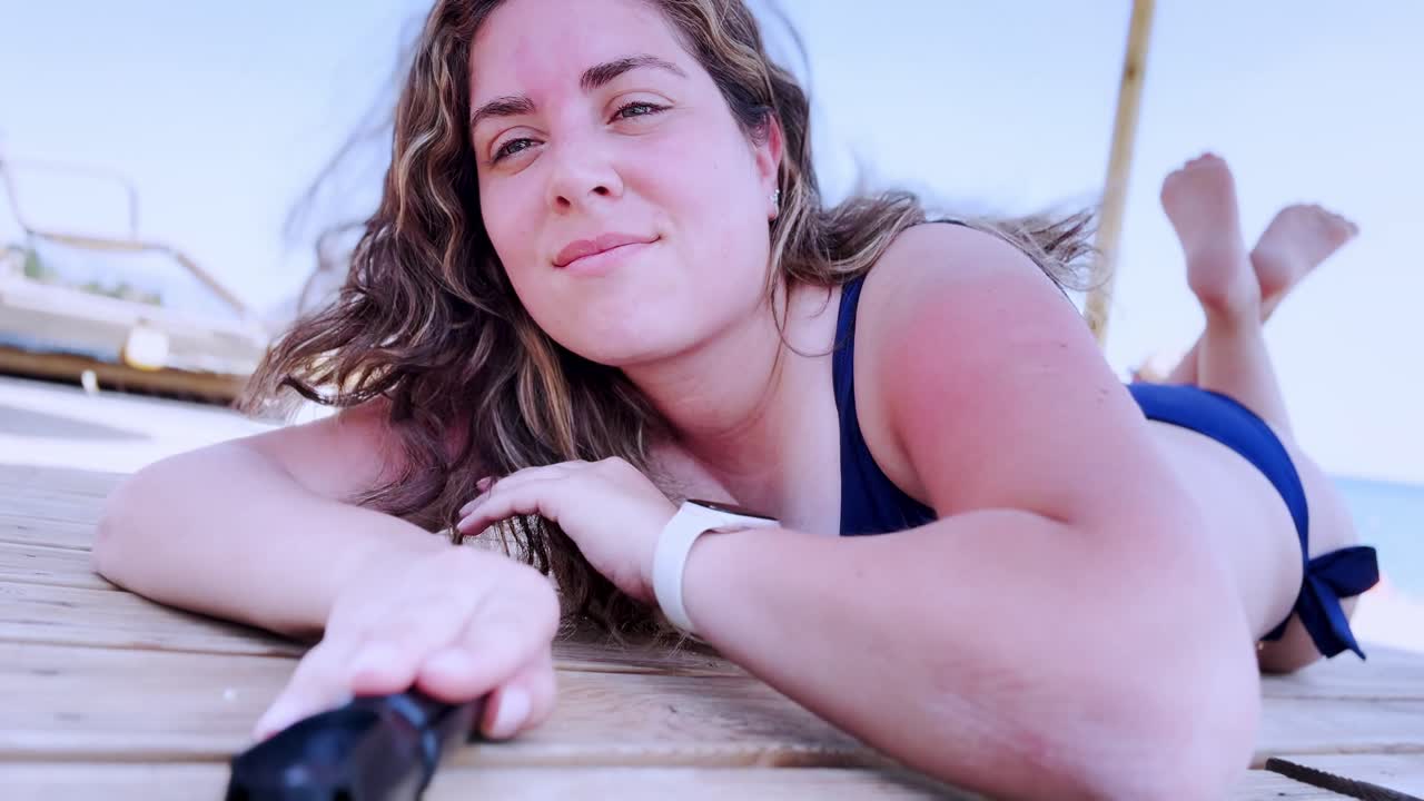 Woman relaxing sunbathing on wooden deck at beach