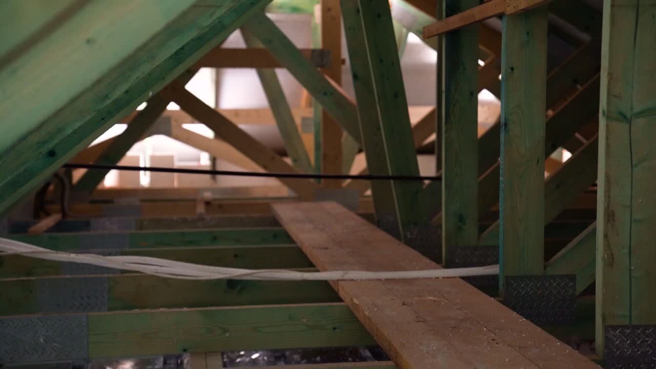 Narrow walkway through timber roof trusses inside attic during building construction
