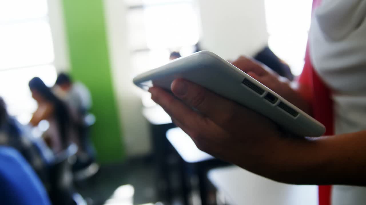 maestro que enseña a los estudiantes en una tableta digital en el aula