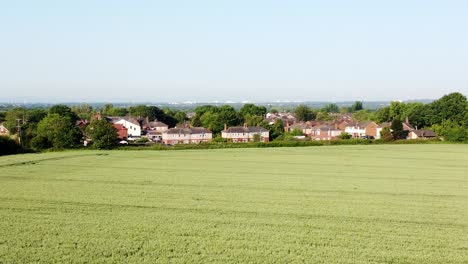 descending drone shot from a beautiful green meadow overlooking residential houses in crouton village farmland united kingdom during a sunny day