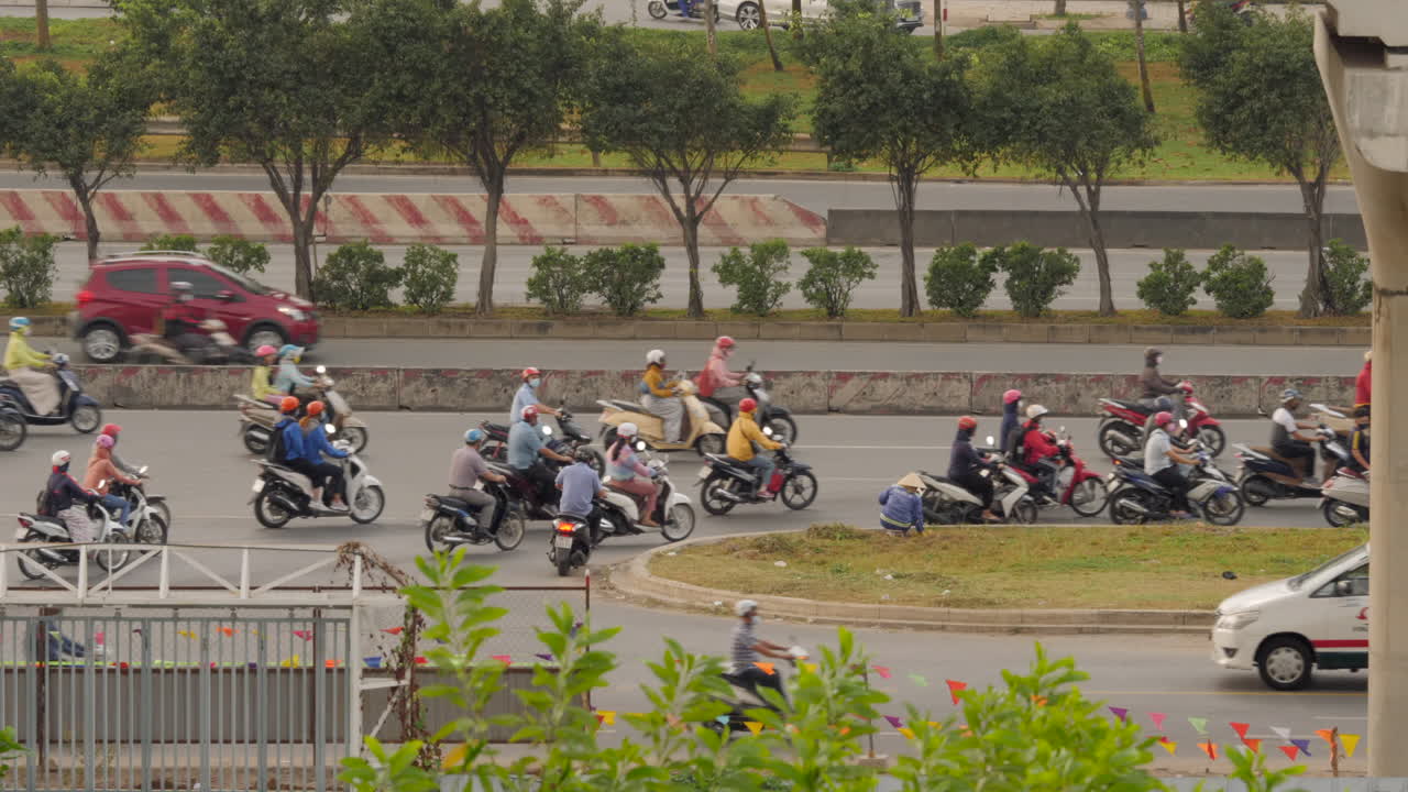 Slowmo shot of many scooters and cars turning on busy highway in Vietnam