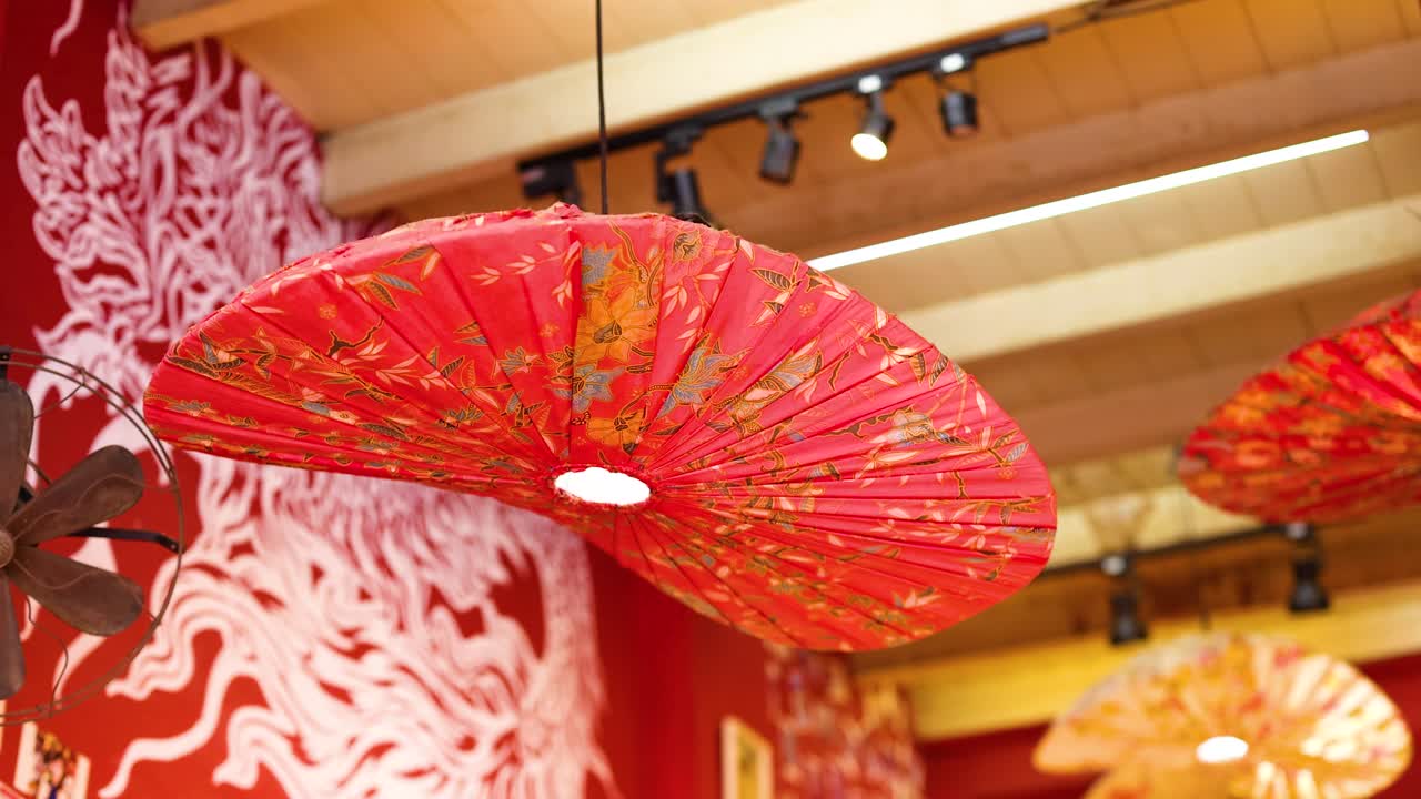 Red lanterns hang in a warmly lit restaurant, creating a vibrant and inviting atmosphere with intricate wall patterns