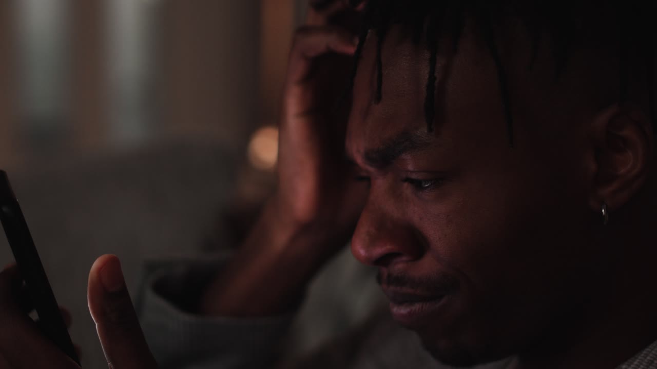 Young black male cringes and reacts angry to what he's seeing on his smart phone