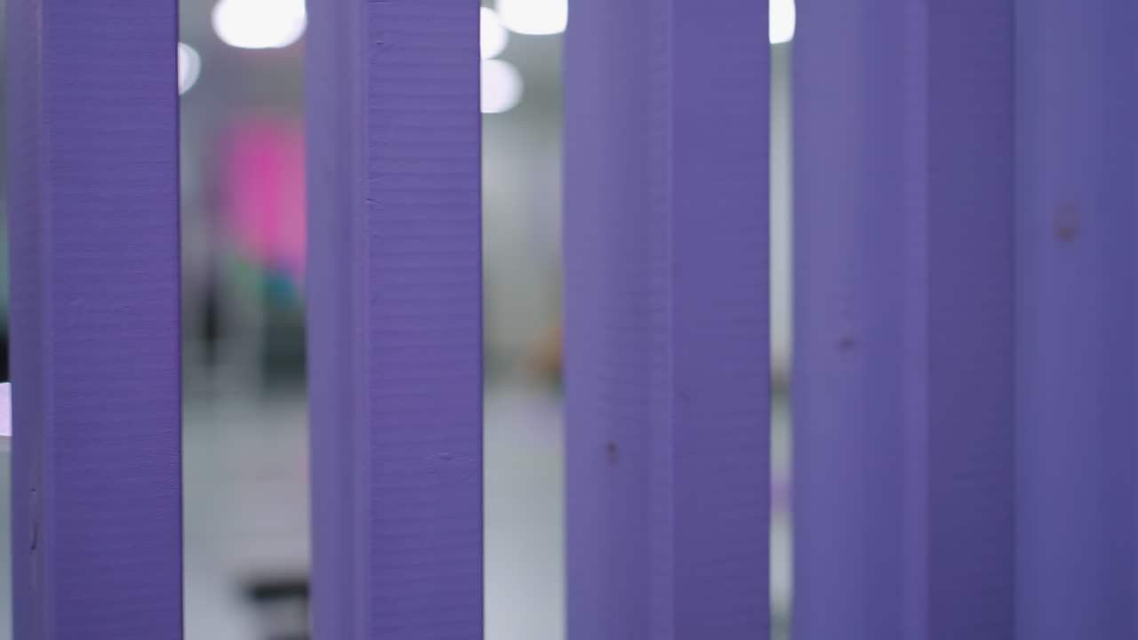 primer plano de la estructura vertical púrpura con un fondo interior borroso, iluminación suave y tonos apagados crean profundidad y contraste, destacando la textura y la estructura de los elementos de primer plano