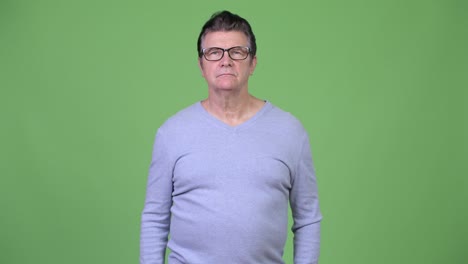 senior handsome man covering eyes not wanting to see something