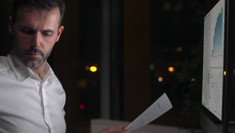 hombre enfocado trabajando con tecnología por la noche