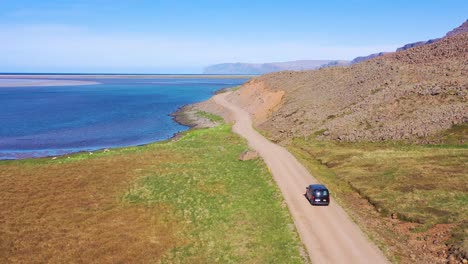 Antenne-über-Einen-Schwarzen-Van,-Der-Auf-Einer-Unbefestigten-Straße-In-Island-In-Der-Nähe-Des-Strandes-Von-Raudisandur-In-Den-Nordwestlichen-Fjorden-Unterwegs-Ist-1