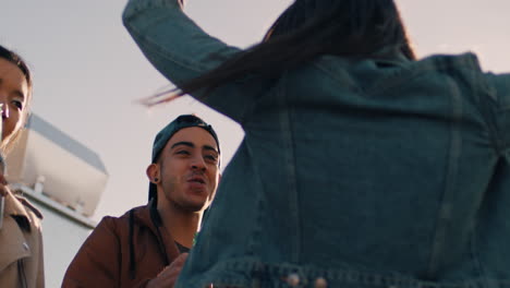 slow-motion-group-of-multiracial-friends-hanging-out-young-asian-woman-dancing-enjoying-rooftop-party-at-sunset-drinking-alcohol-having-fun-on-weekend-celebration