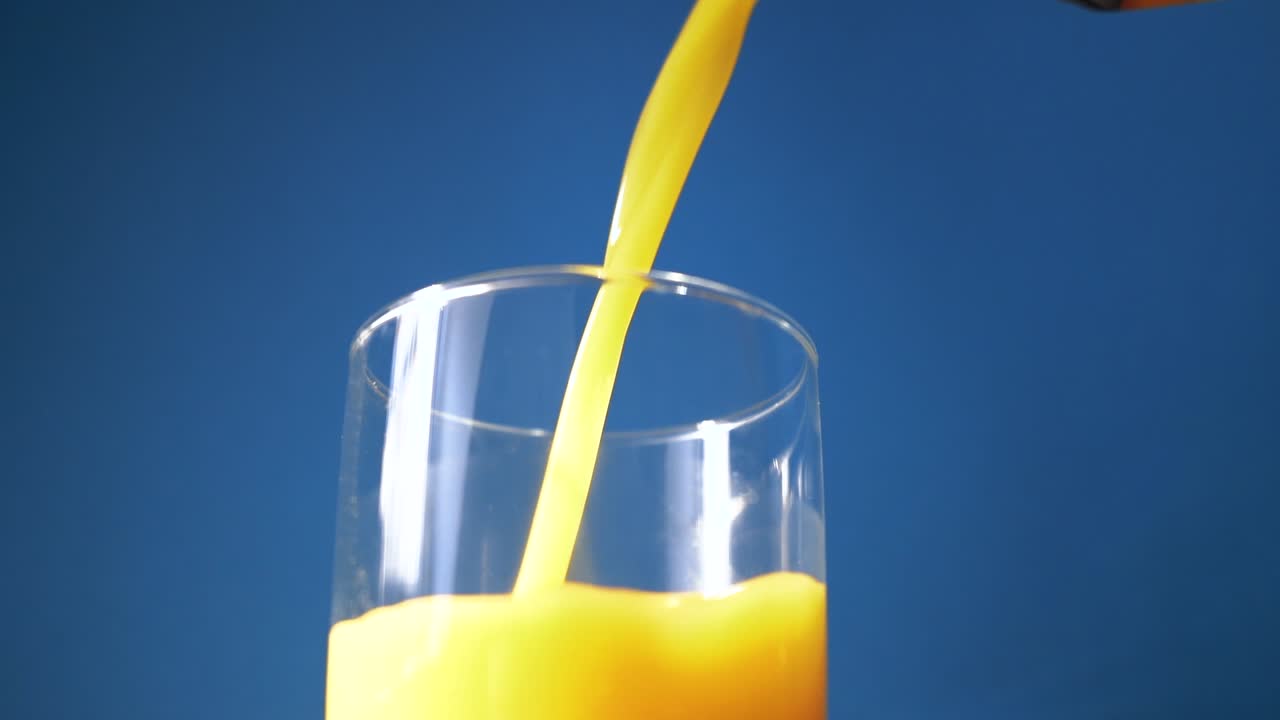 Il succo d'arancia viene versato in un bicchiere al rallentatore